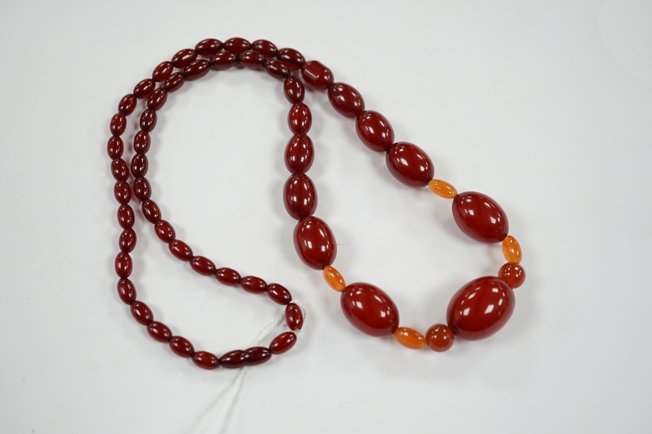 A single strand graduated simulated cherry amber bead necklace, with four simulated orange amber beads, 66cm, gross weight 84 grams.